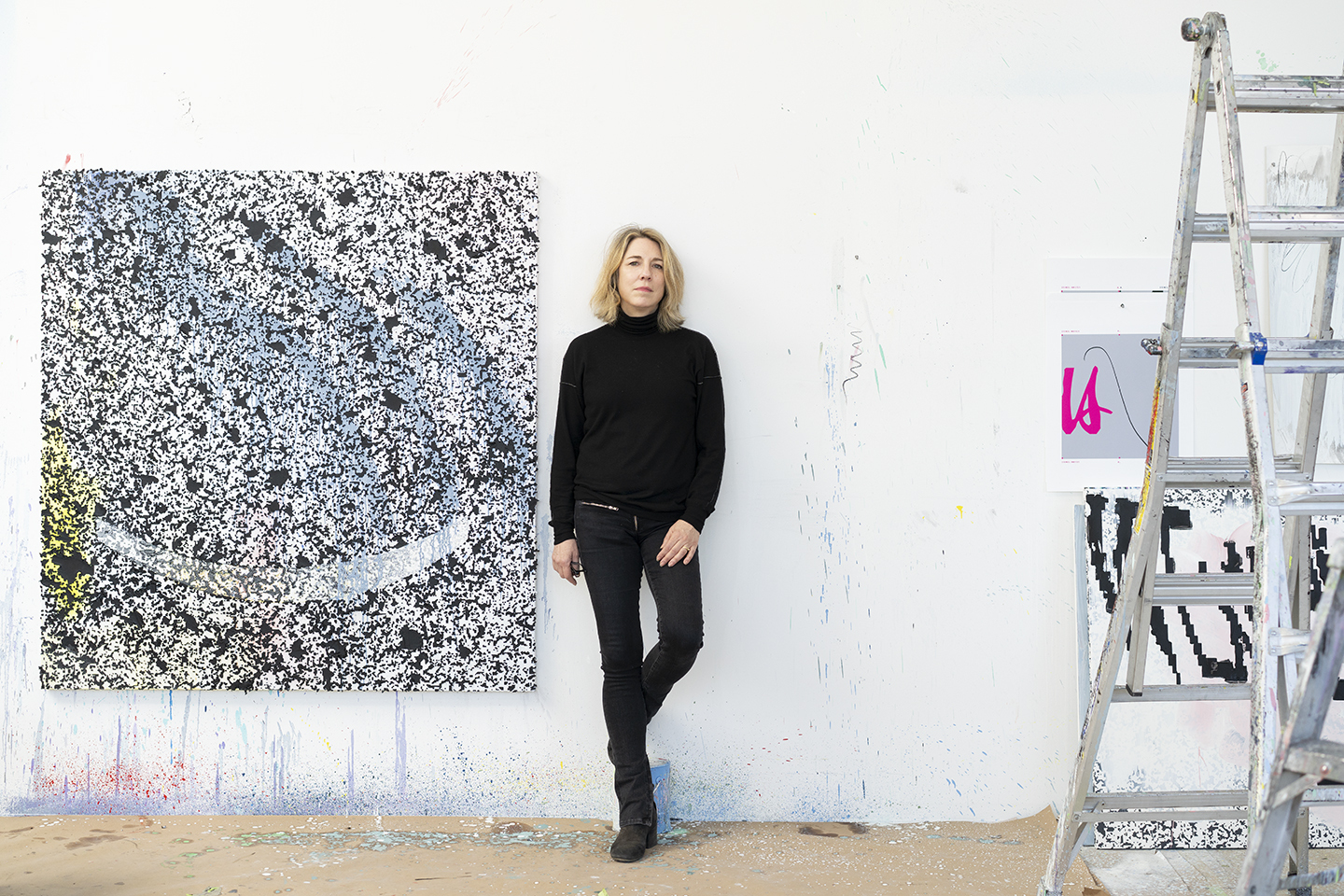 a woman stands next to a large abstract painting